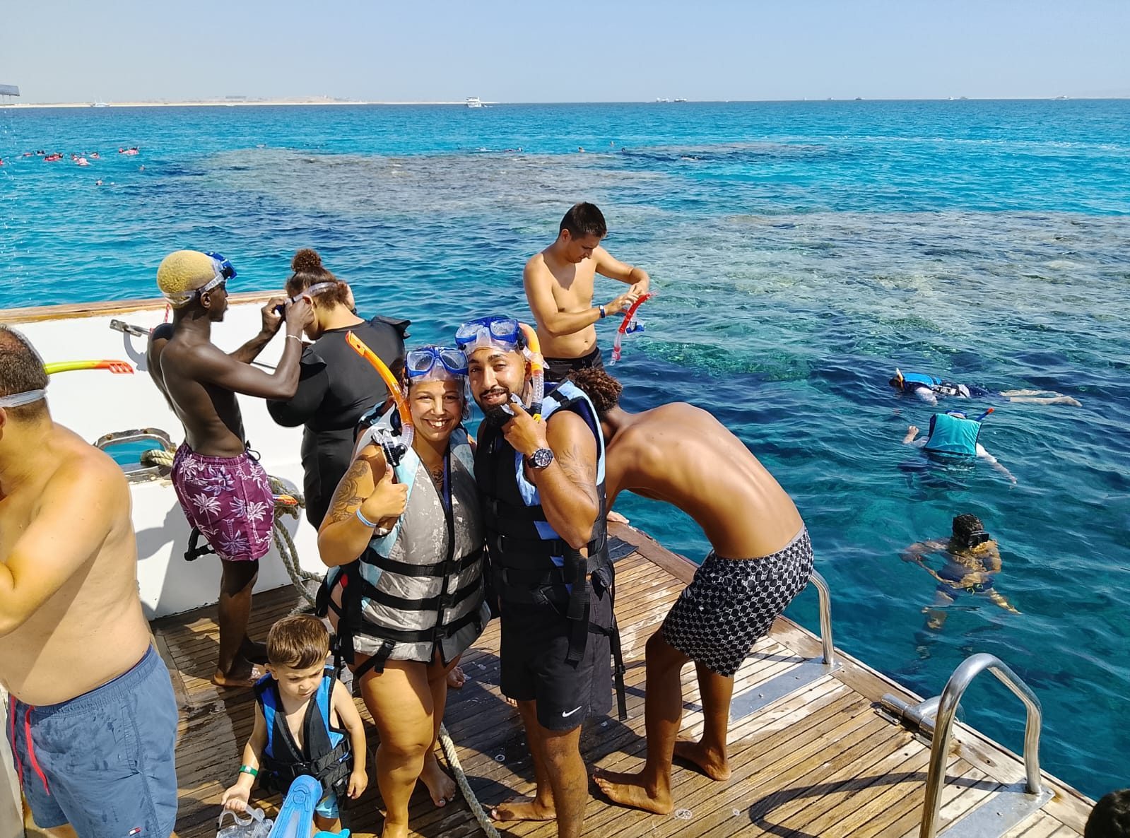 Golden Sand guests in life vests and snorkel masks getting ready on a boat deck above a Red Sea reef