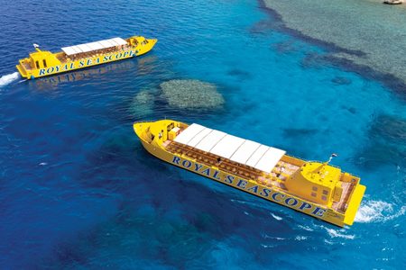 Aerial view of two yellow Royal Seascope tour boats with white awnings over turquoise reef water
