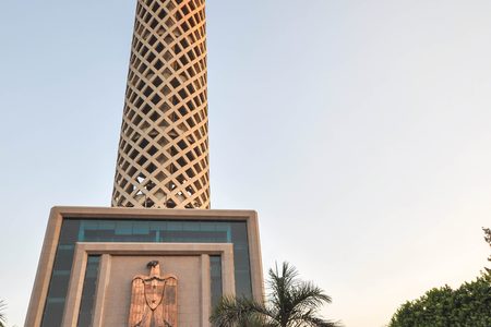 مآذن وقباب مسجد تاريخي ترتفع فوق الأشجار في القاهرة الإسلامية تحت سماء ضبابية