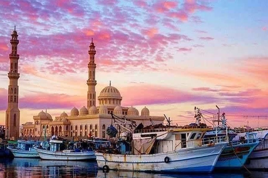 El Mina Mosque rising behind fishing boats in Hurghada harbor at sunset under a pink sky