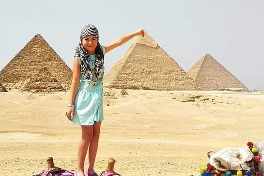 A young visitor posing in front of the pyramids of Giza