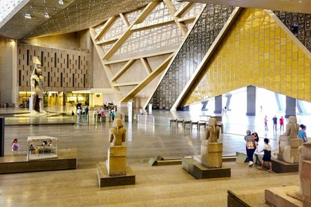 Visitors among ancient pharaonic statues in the soaring atrium of the Grand Egyptian Museum