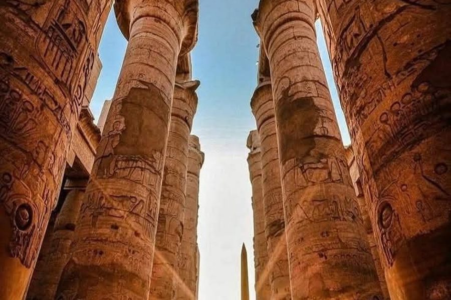 Sunlight streaming between towering carved columns of the Hypostyle Hall at Karnak Temple, Luxor