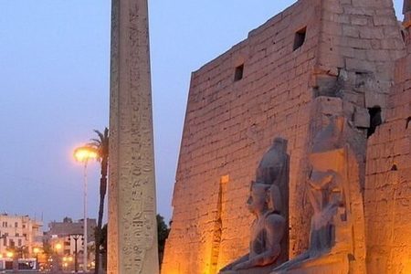 Luxor Temple entrance at dusk with the obelisk and seated statues in front of the floodlit pylon