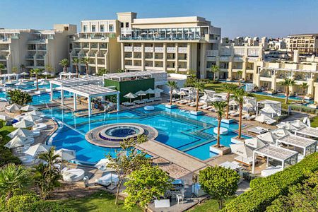 فندق منتجع في الغردقة (Hurghada) يضم مسبحًا كبيرًا وكراسي استلقاء للتشمس زرقاء ومباني وردية على الطراز المغربي