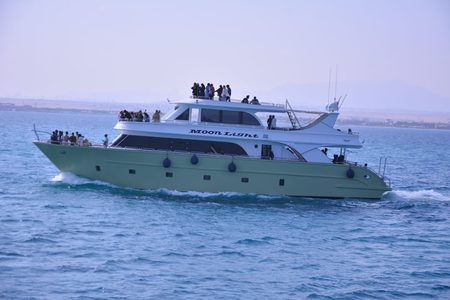 Pale green and white yacht Moon Light cruising on open blue water with guests on deck near Hurghada