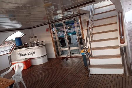 Covered deck of the Moon Light yacht with a bar counter, cooler box, stairs to the upper deck and glass doors