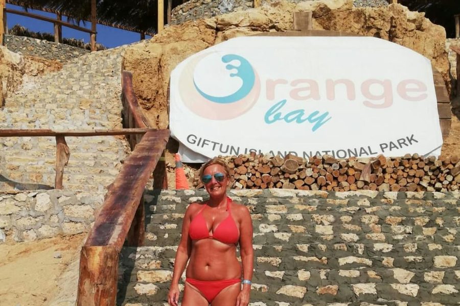 Tourist standing on stone steps below the Orange Bay sign in Giftun Island National Park