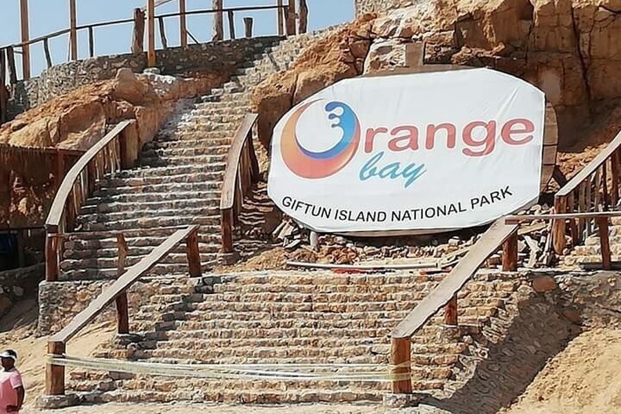 Orange Bay sign reading Giftun Island National Park beside a stone staircase with wooden railings