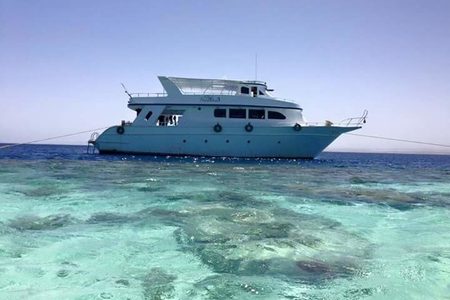 White tour boat anchored over turquoise coral reef shallows on a boat trip from Hurghada
